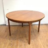 A teak extending dining table by Mackintosh, Kirkcaldy, the circular top enclosing a hinged