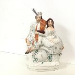 A Victorian flatback Staffordshire " Poormans Clock" ornament of a seated Scottish Couple. (h.36cm x