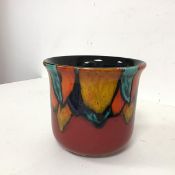 A Poole pottery vase, with flared lip and polychrome stylised leaves design on red ground, stamped