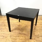 An ebonised ash dining table, the hinged oblong top above an angular frieze with central cut out,