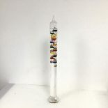 A Galileo thermometer with twelve internal bobbles, with coloured liquids, measuring from 15 degrees