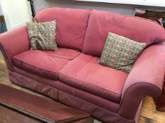 A country house style two seater sofa with outswept arms and squab cushions, in pink loose cover