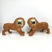 A pair of Staffordshire lions, both with gilt decoration and glass eyes (repairs to feet) (h.27cm