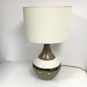 A 1970s style table lamp, the ceramic base of bulbous form tapering to a slender neck, with linen