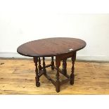 An oak drop leaf coffee table, the oval top with moulded edge, leaves opening on gatelegs, with