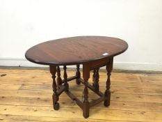 An oak drop leaf coffee table, the oval top with moulded edge, leaves opening on gatelegs, with