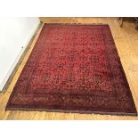 A hand knotted Turkoman style carpet, the madder field with three rows of indigo framed gulls,