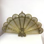A brass metamorphic peacock feather style firescreen with nine folding panels, folding above a