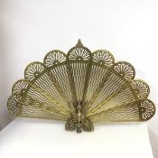 A brass metamorphic peacock feather style firescreen with nine folding panels, folding above a