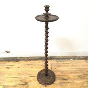 An Edwardian walnut candle stand, the dished top with raised sconce on a spiral turned shaft and
