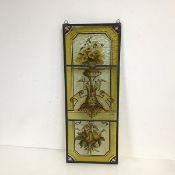 A leaded stained glass triptych panel, the panels in honey yellows depicting a vase of flowers and