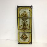 A leaded stained glass triptych panel, the panels in honey yellows depicting a vase of flowers and