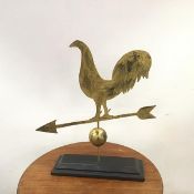 A naive art sculpture in the form of a wind vane with a cockeral on an arrow, cut copper with gold