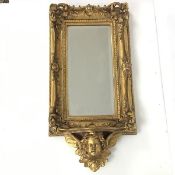 A rococo style wall mirror, the rectangular bevelled glass surrounded by an elaborate frame, with