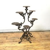 A cast iron plant stand, the frame incorporating opposing C scrolls supporting pierced circular