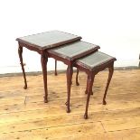A set of three nesting tables, all with tooled leather tops under glass, with moulded edges and