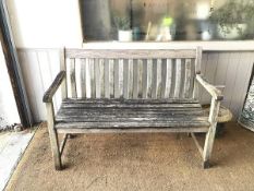 An attractively weathered garden bench with slightly curved back slats, one arm a/f (86cm x 122cm