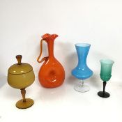 A collection of glassware including an orange glass ewer, the folded spout over a long neck, with