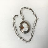 A silver locket of oval form with carved shell cameo to front (4cm x 5cm) on a silver belcher link