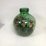 A large glass bottle marked Viresa, includes sythetic flowers and leaves in soil (h.36cm x d.28cm)