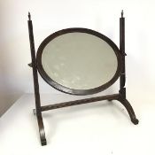 An Edwardian mahogany swing mirror of oval form, on twin carved supports (50cm x 48cm)