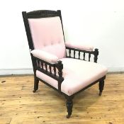 A late 19thc later ebonised armchair, the carved frame enclosing a pale pink buttoned upholstery, on