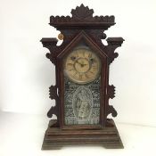 An early 20thc American mantel clock of unusual design, the moulded surmount over a hinged door with