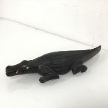 A 1920s African carved ebony paperweight in the form of an alligator, with bone eyes and teeth (some