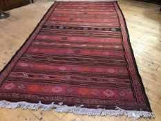 A kelim flatwoven rug, the horizontal bands with stylised lozenges and floral bands, on a pink poppy