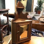 An Edwardian walnut wall corner cabinet with shaped sides and centre mirror door, enclosing a