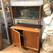 A 1950s/60s teak two section cocktail cabinet with twin sliding glazed panel doors enclosing a