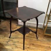 An Edwardian mahogany two tier occasional table, with shaped top, on carved leaf foliate support (