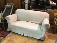 A 1920s two seater drop end sofa upholstered in calico with linen style loose cover, on ball style
