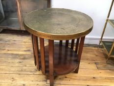 A 1920s/30s walnut framed Eastern brass top two tier ship's occasional table with engraved panel top