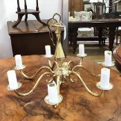 A modern seven arm brass chandelier with baluster shaped body and scroll arms ending in faux candles
