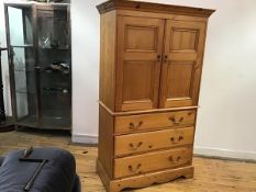 A neat modern pine linen press, the two cabinet doors opening to a shelved interior, above three