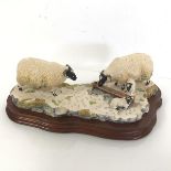 A Border Fine Arts resin figure of Two Sheep and Two Lambs feeding at a Trough, with mahogany
