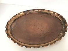 An oval copper salver, with raised scalloped edge (50cm x 41cm)