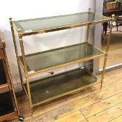 A brass and glass 1970s etagere, each of the three tiers with inset smoked glass panels, on reeded