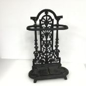 A cast iron umbrella stand with classically inspired pierced back plate over a removeable drip