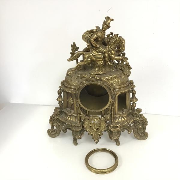 A brass mantel clock surround, ornately decorated with C scrolls, fruit, leaves and flowers and a