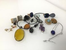 An assortment of polished stone pendants including amethyst and lapis lazuli, some mounted in