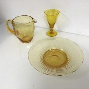 A collection of amber coloured glass including water jug, dish with swirled ribbed pattern and a