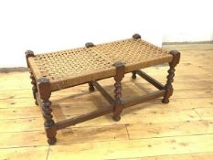 An early 20thc oak footstool, with rush top supported by six barley twists and box stretchers (