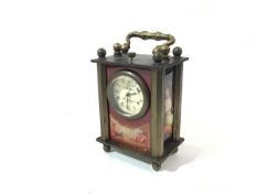 An Omega brass mounted miniature four glass style clock, with glazed panels depicting famous