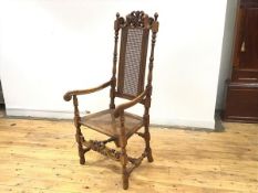 A Charles II style oak chair, the carved top rail above a caned panel back over a caned seat, on