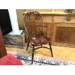 An elm Windsor style spindle back kitchen chair with shaped saddle seat raised on turned splay