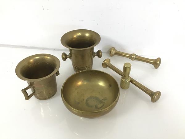 A pair of brass mortars of bell form (tallest: 10cm x 13cm x 10cm), with pestles and another bowl