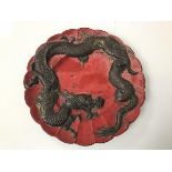 An early 20thc Japanese dish, with bronze dragon on red ground, with scalloped edge (d.30cm)