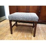 A mahogany footstool with upholstered top in geometric pattern, on straight supports united by H